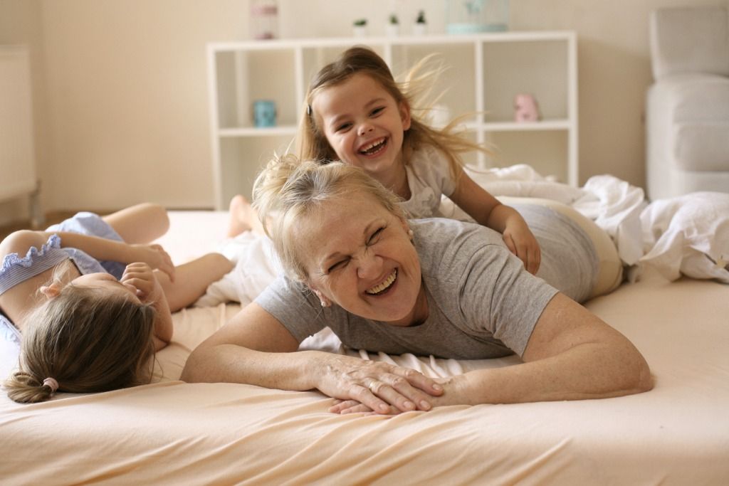 Two children playing on a bed with their childcarer