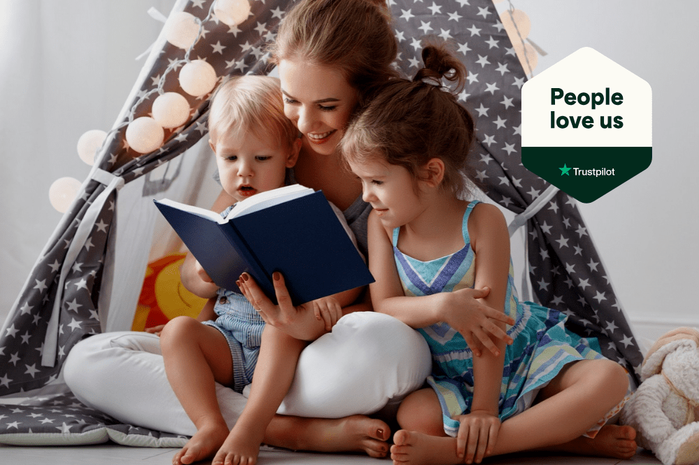 Childcarer reading two children a bedtime story in a play tent